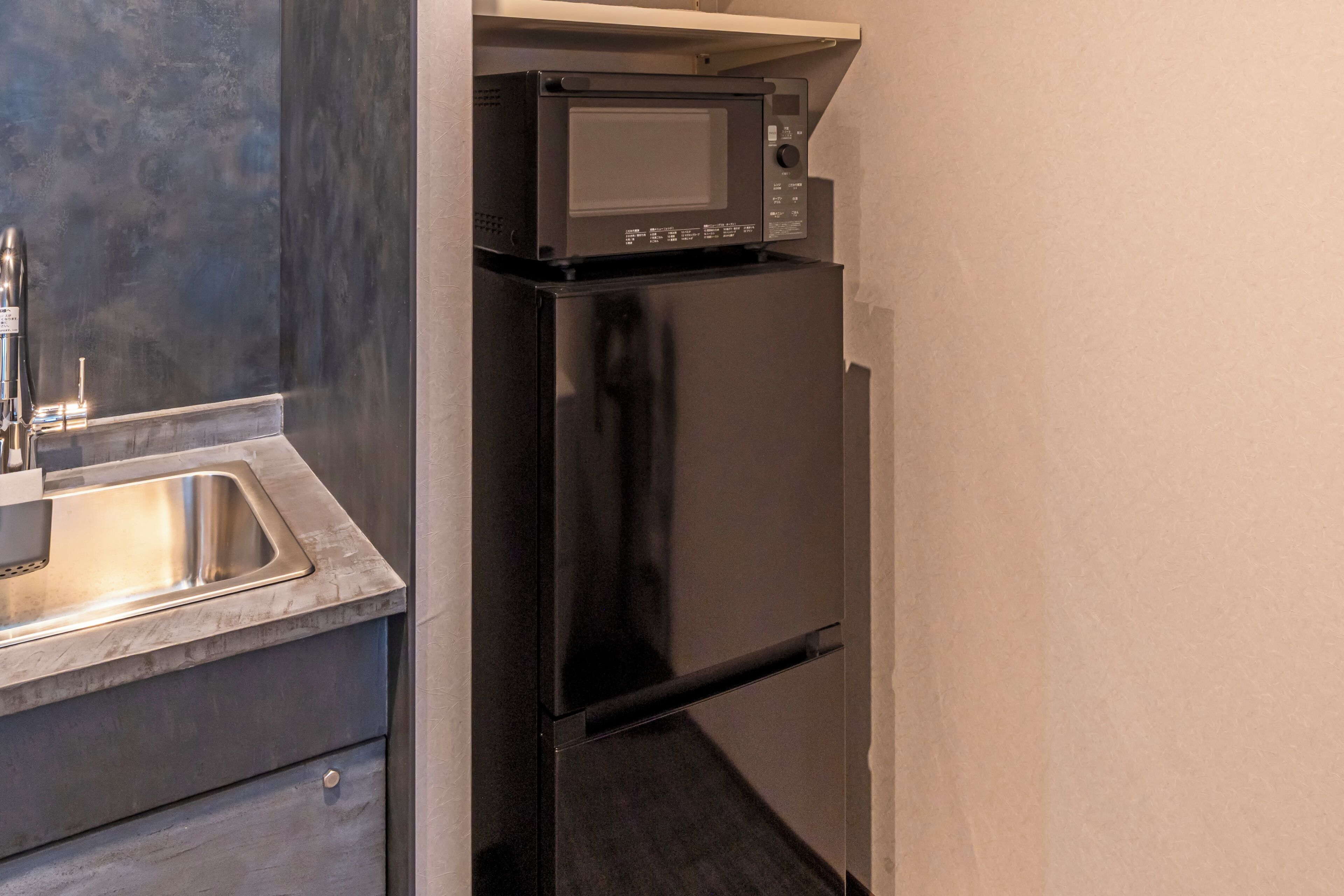 Eine kleine Küche mit einem Edelstahl-Kühlschrank, einer Mikrowelle und einem Spülbecken.