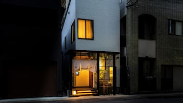 Un edificio moderno con entrada de vidrio y una pequeña escalera que lleva a la puerta.