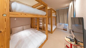A bunk bed room with a TV, a small table with electronic devices, and a window with curtains. - Asobiyado Rin (Kagoshima-shi)
