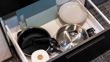 Un cassetto della cucina con pentole e utensili, tra cui una padella, una pentola e un coperchio.