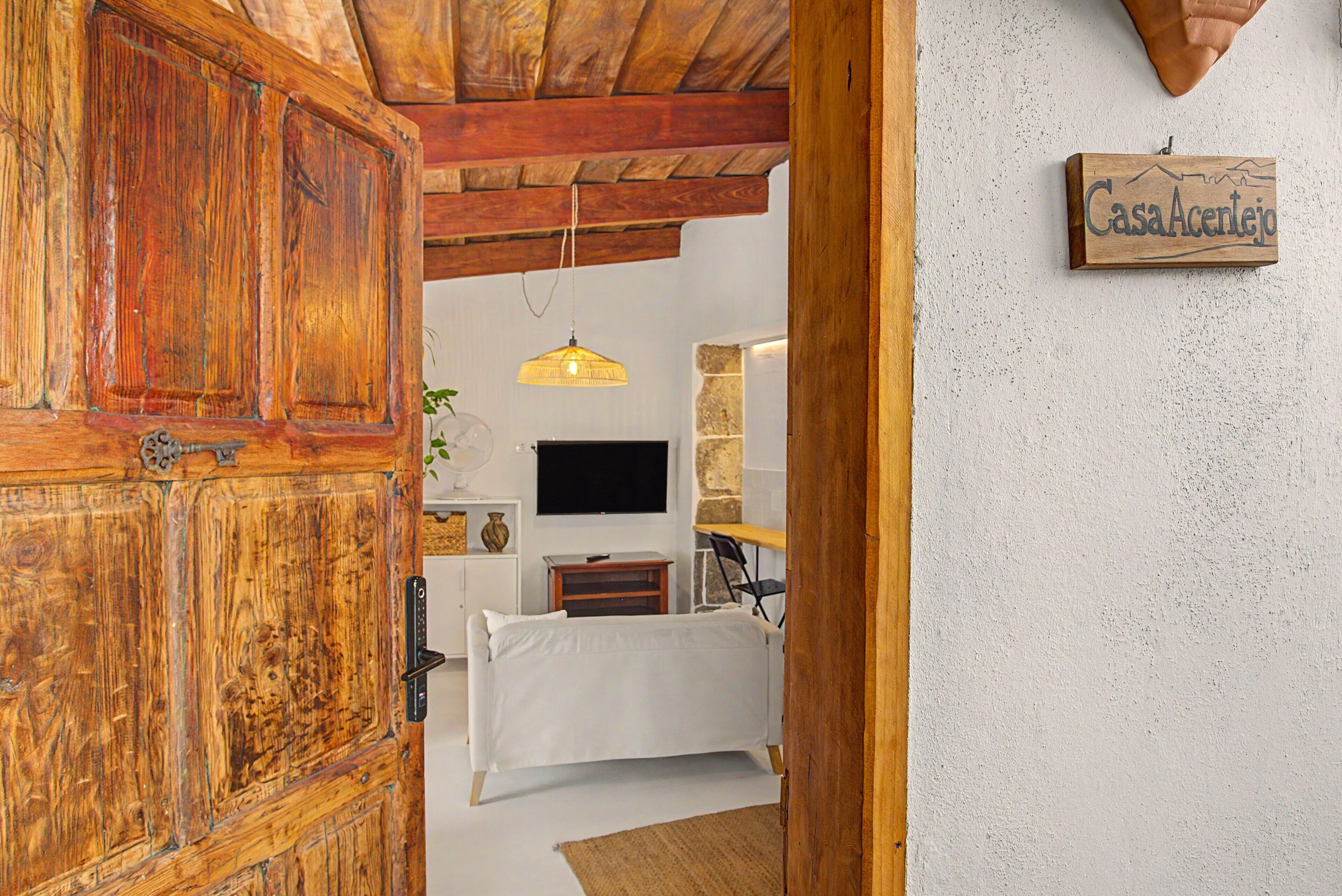 A room with a wooden door, a bed, a television, and a wall-mounted sign.
