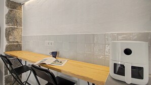 A kitchen with a wooden table, two black chairs, a coffee maker, and a tiled backsplash.