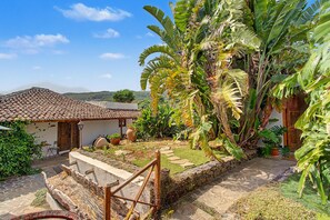 Una casa tradicional con techo de tejas, una escalera de piedra y exuberante vegetación tropical.