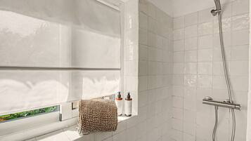 A bathroom with a shower, a window with a towel, and toiletries.