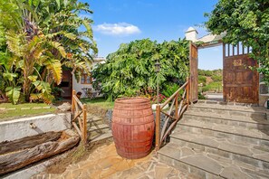 A wooden barrel in a garden with a stone staircase leading to a wooden gate.