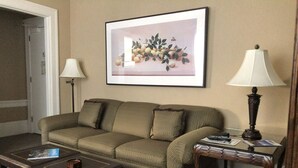 Un soggiorno con un divano, un tavolino da caffè, un comodino con una lampada e un quadro appeso al muro.