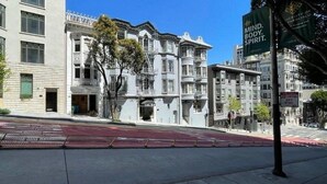 Una vista di strada con edifici in stile vittoriano, una corsia ciclabile rossa e un cartello per l'Università di San Francisco.