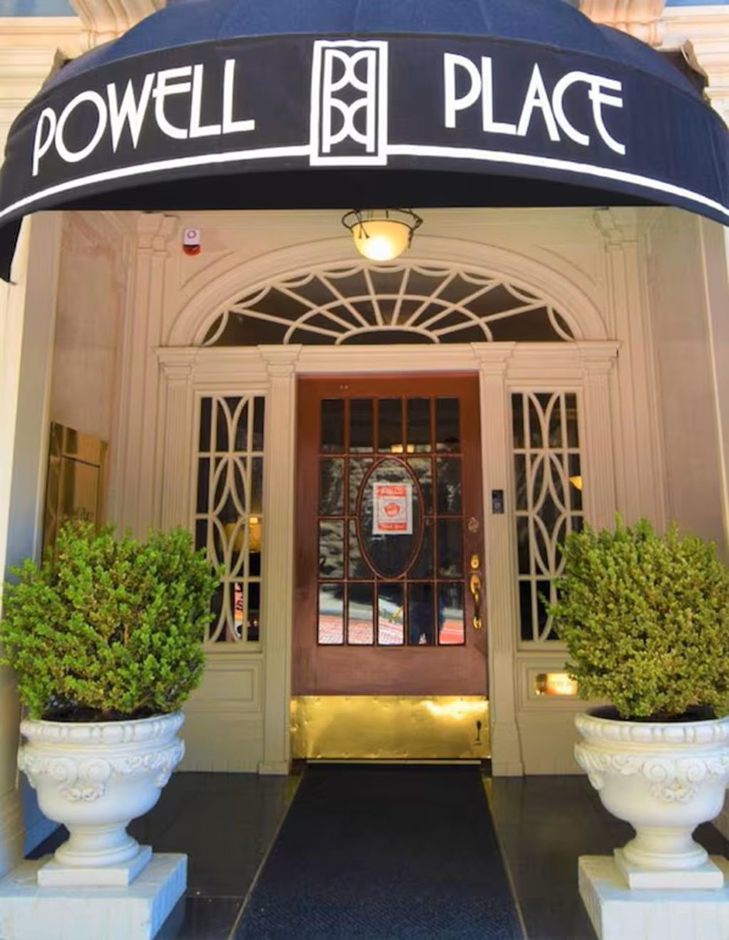 La entrada a un hotel con un cartel que dice 'POWELL PLACE' sobre la puerta.