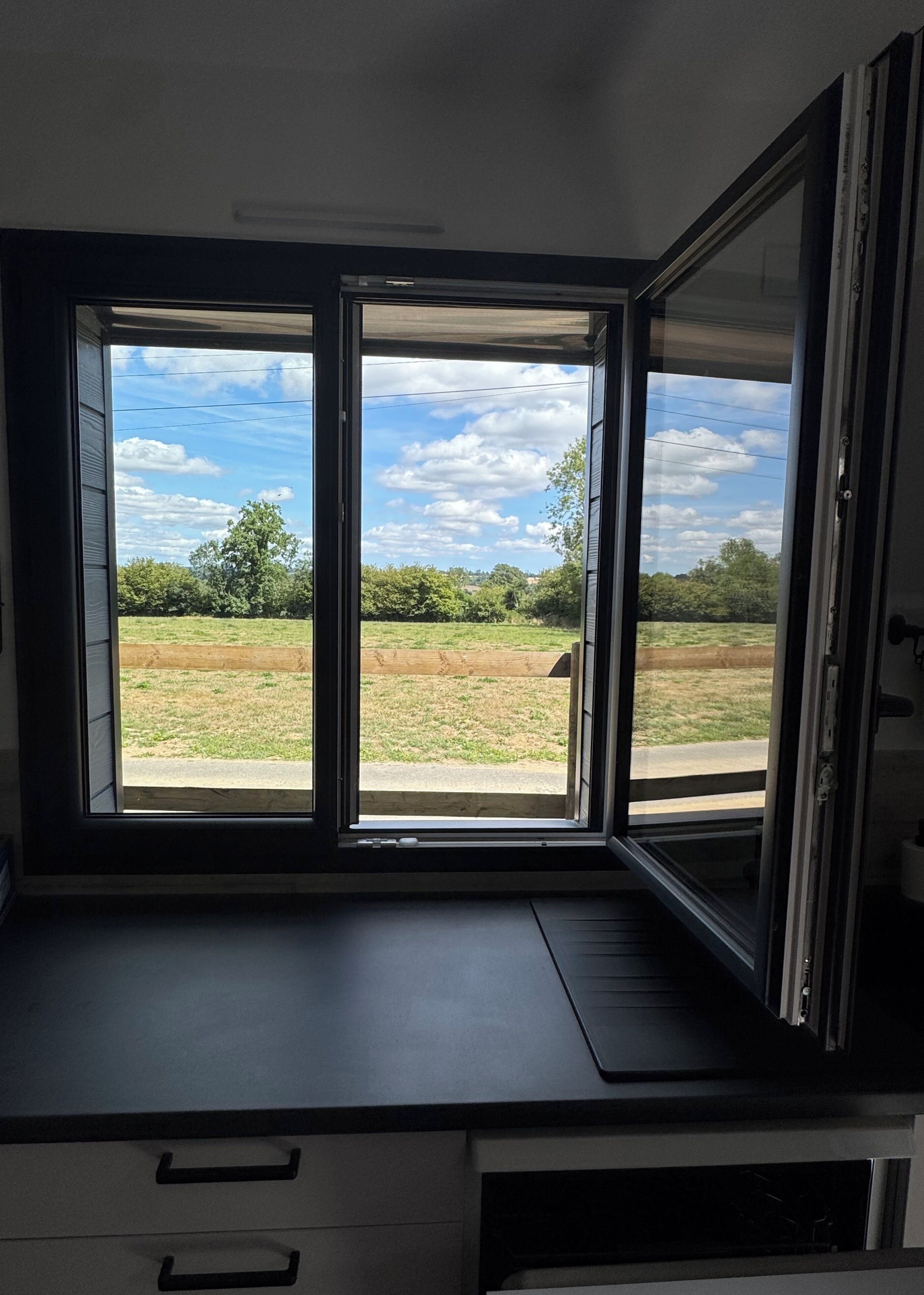 Una habitación con un amplio ventanal que ofrece vista a un campo y árboles.
