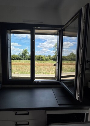 A room with a large window offering a view of a grassy field and trees.