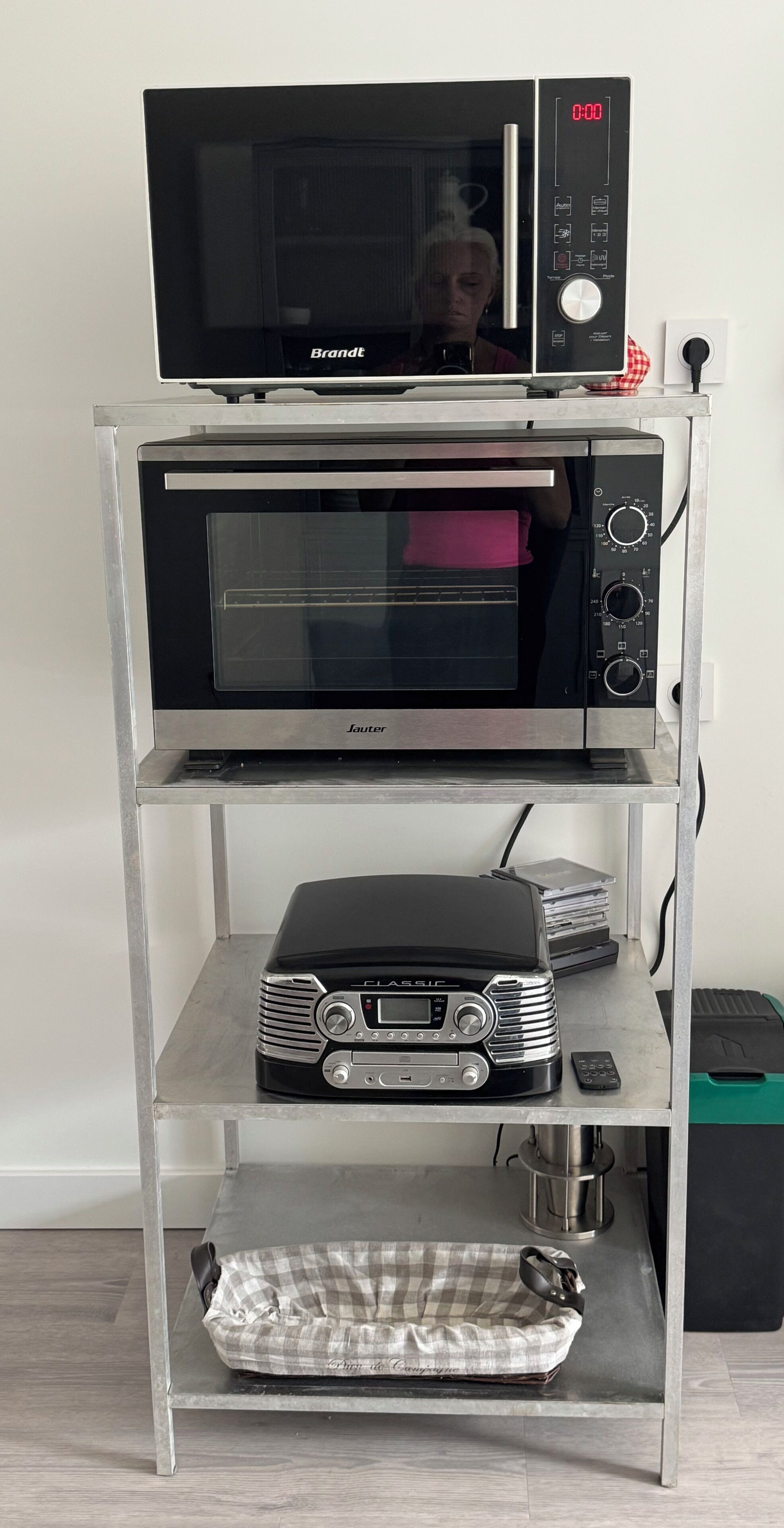 A kitchen with a Brandt microwave on top of a Sauter oven, a Classic toaster, and a bag of groceries on the lower shelf.