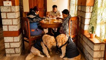 Un comedor con una mesa redonda, sillas de madera y una pared de ladrillo.