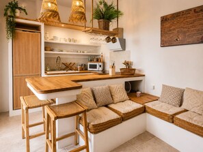Eine moderne Küche mit Holzarbeitsplatten, einem eingebauten Ofen und einer Sitzecke mit gewobenen Kissen.