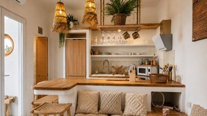 Une cuisine moderne avec des plans de travail en bois, un coin salon intégré et des luminaires suspendus en osier.