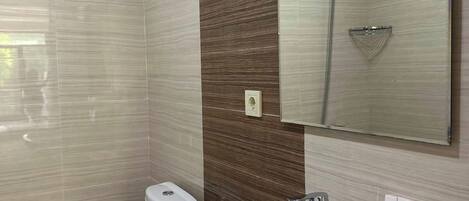 Un baño moderno con inodoro, lavamanos y ducha.