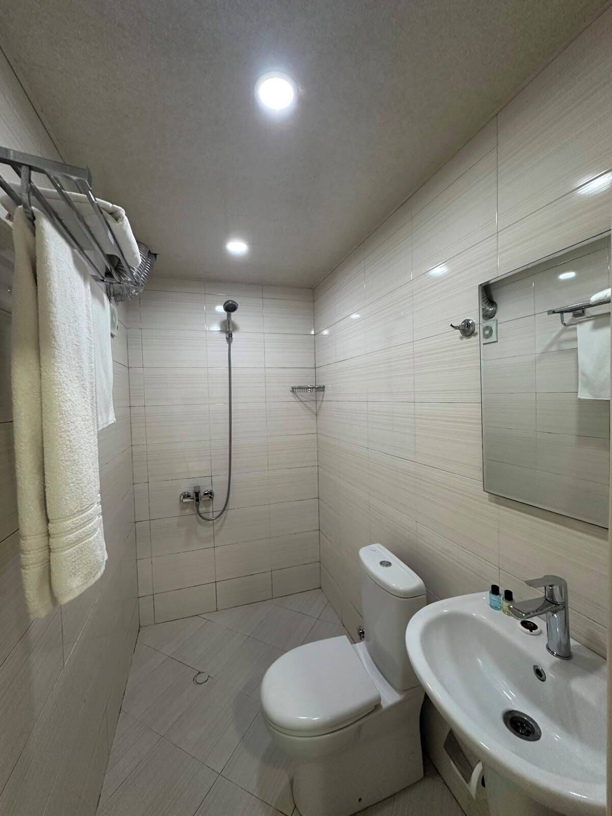 Un baño pequeño y moderno con inodoro, lavamanos y ducha.