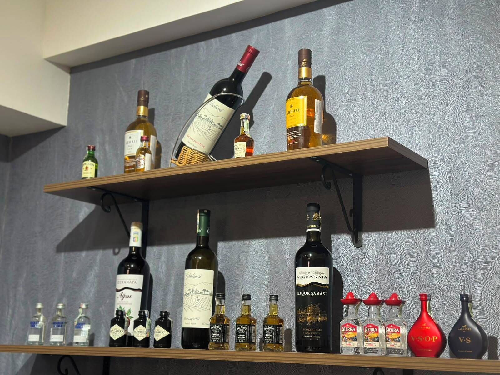 Two wooden shelves with various bottles of alcohol, including wine and spirits.