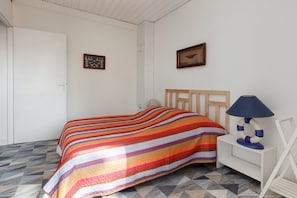 A bedroom with a bed, a nightstand, a lamp, and two framed pictures on the wall. - Holiday Home 'Petite Frégate' (La Turballe)