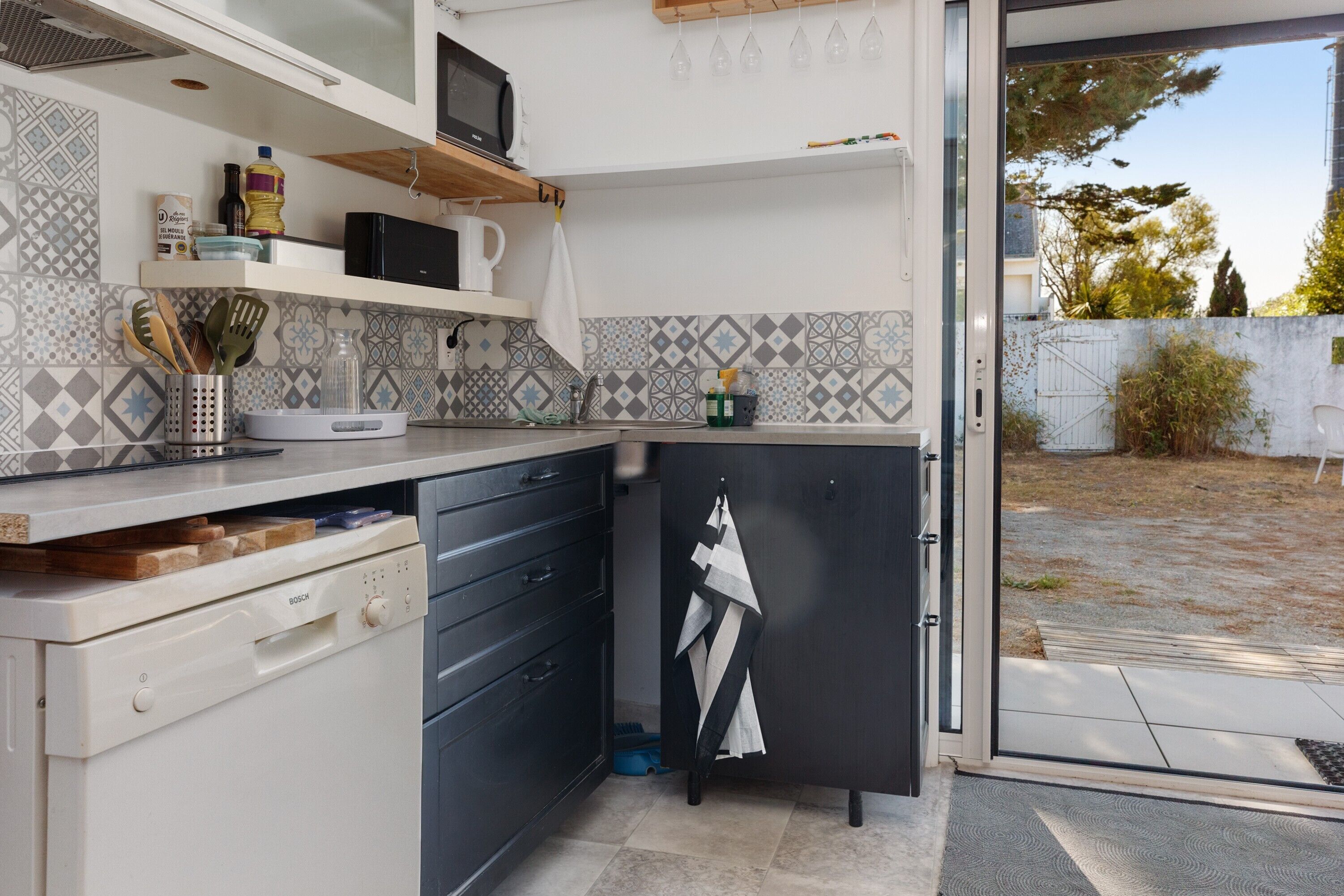 Una cocina compacta equipada con microondas, un lavaplatos y lavavajillas Bosch.