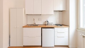 A compact kitchen with white cabinets, a wooden countertop, a sink, a coffee maker, and a dishwasher. - Dante Art Studio (Roma)