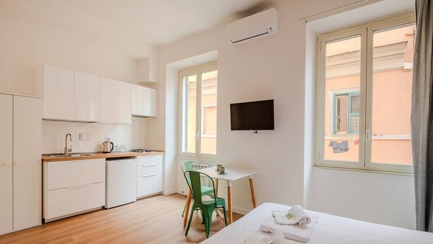 A hotel room with a bed, a desk, a chair, a TV, and a window. - Dante Art Studio (Roma)