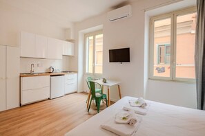 A hotel room with a bed, a desk, a chair, a TV, and a window. - Dante Art Studio (Roma)