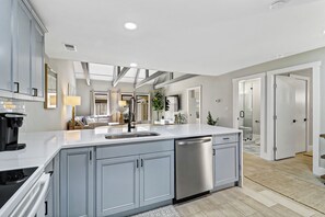 A modern kitchen with a large island, built-in appliances, and a view into the living area. - Sunset Rentals | Queens Grant 616 | Dog Friendly (Hilton Head Island)