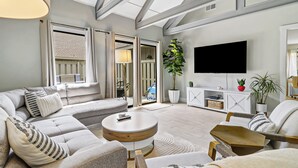 A modern living room with a sofa, coffee table, and a TV mounted on the wall. - Sunset Rentals | Queens Grant 616 | Dog Friendly (Hilton Head Island)
