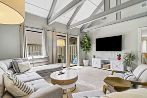 Ein modernes Wohnzimmer mit einer Couch, einem Couchtisch und einem an der Wand befestigten Fernseher.