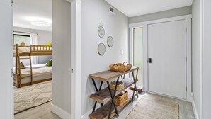 A hallway with a bunk bed, a wooden table with baskets, and a door. - Sunset Rentals | Queens Grant 616 | Dog Friendly (Hilton Head Island)