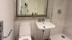 Ein modernes Badezimmer mit Toilette, Waschbecken und Dusche.