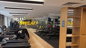 Ein Fitnessraum mit Laufbändern, Kraftgeräten und Holzboden.