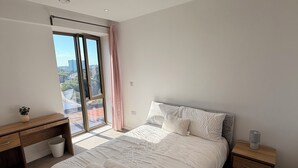 Ein Schlafzimmer mit einem großen Bett, einem Schreibtisch und einem Fenster mit Blick.