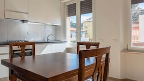 Een moderne keuken met witte kasten, een gasfornuis en een eettafel met stoelen.
