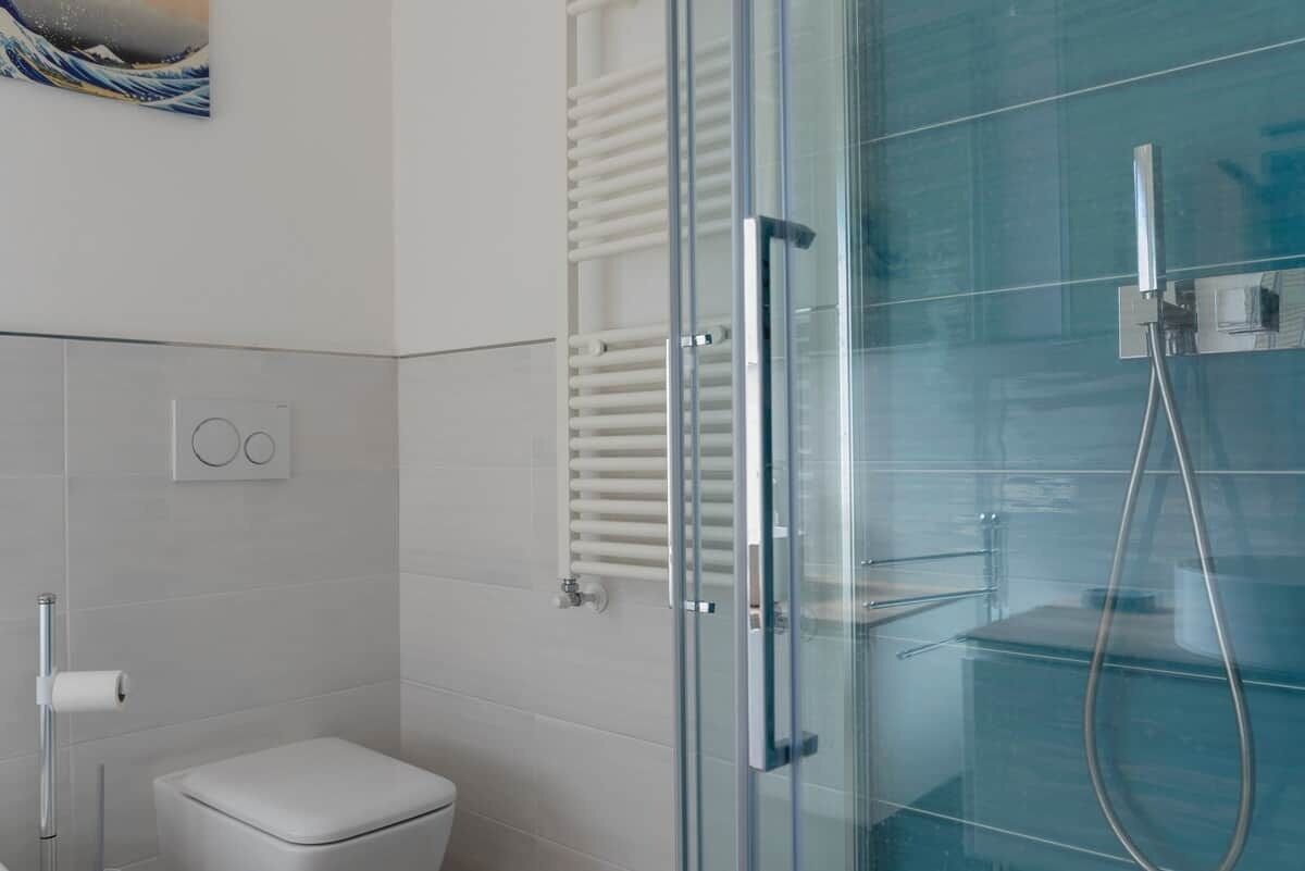 Ein modernes Badezimmer mit Duschkabine aus Glas, Toilette und Handtuchhalter.