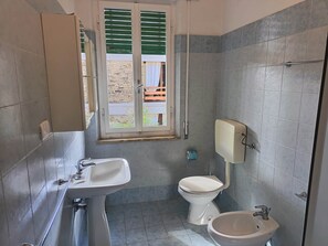Une salle de bain équipée de toilettes, d’un bidet et d’un lavabo.