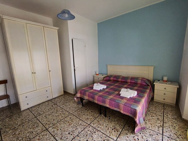 Une chambre à coucher avec un lit, une armoire, une table de chevet et une porte.