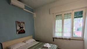 A bedroom with a bed, a poster on the wall, and a window with blinds. - 454 Orchidee Mare (3-seater) (Marina di Grosseto)