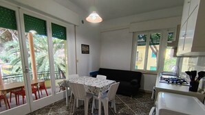 A compact kitchen with a dining area, a sofa, and a view through the window. - 454 Orchidee Mare (3-seater) (Marina di Grosseto)