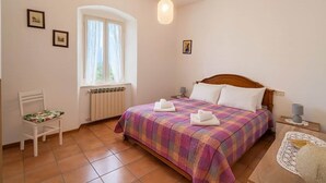 A bedroom with a bed, a chair, a window, and a radiator. - Casa Maria Amiata: A Cozy House Amid Nature and Comfort (San Lorenzo)