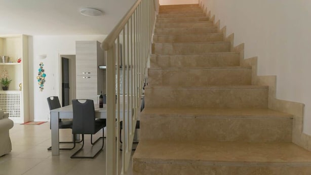 A staircase leading to an upper floor, a dining area with a table and chairs, and a kitchen area with cabinets and appliances. - To complete (Grosseto)