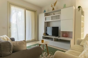 A living room with a sofa, a coffee table, a TV, and a sliding glass door. - To complete (Grosseto)