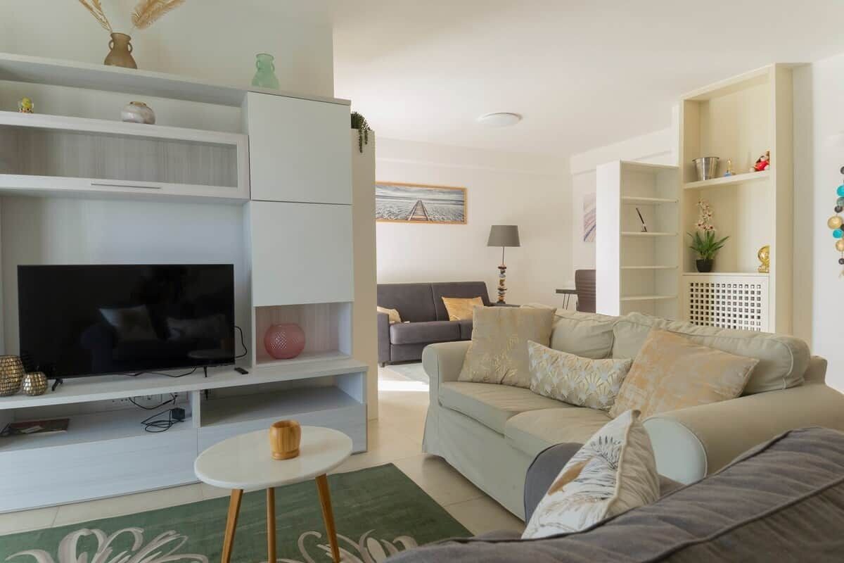 A living room with a TV, sofa, and shelves.