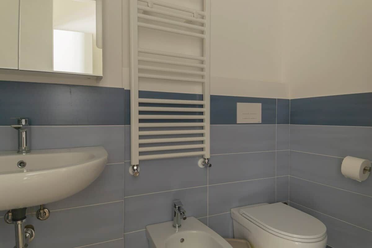 Ein Badezimmer mit einem weißen Waschbecken, einer Toilette und einem Handtuchhalter.