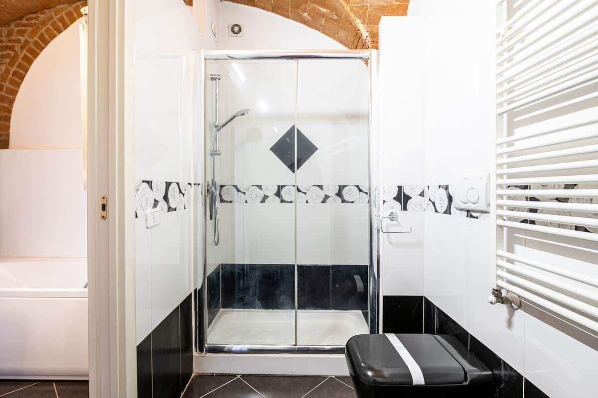 A shower with a glass door, a bench, and a tiled wall with a diamond pattern.
