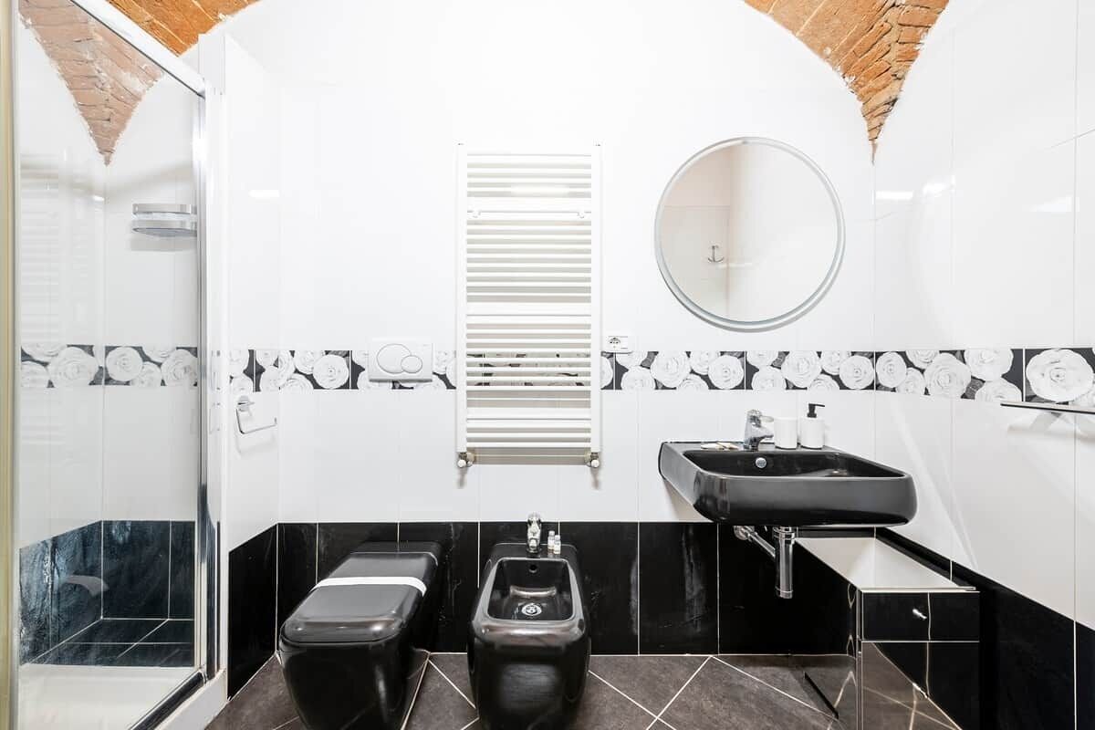 A bathroom with a toilet, bidet, sink, and mirror.