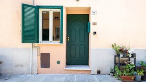 A building with a green door, a window with green shutters, and a small outdoor planter with plants. - [Historic Center] Suite Medicea - hydro tub - A/C (Grosseto)