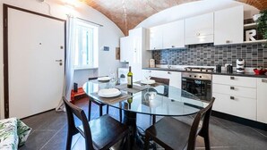 A modern kitchen with white cabinets, a glass dining table, and a brick ceiling. - [Historic Center] Suite Medicea - hydro tub - A/C (Grosseto)