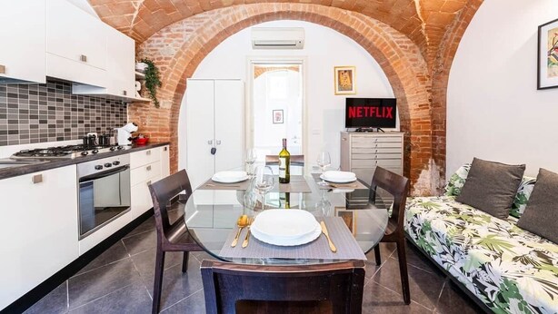 A modern kitchen with a brick archway, a dining table set for two, and a sofa with a tropical print. - [Historic Center] Suite Medicea - hydro tub - A/C (Grosseto)