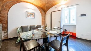 A dining area with a glass table, chairs, and a brick wall. - [Historic Center] Suite Medicea - hydro tub - A/C (Grosseto)